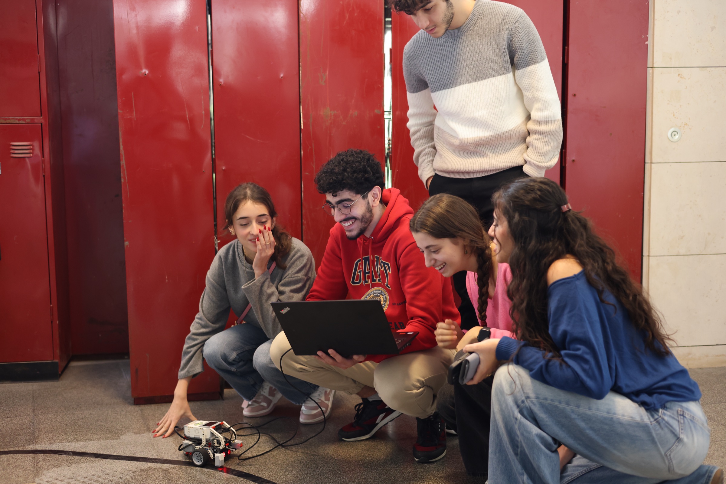 MSFEA students collaborating around a laptop and mobile robot.