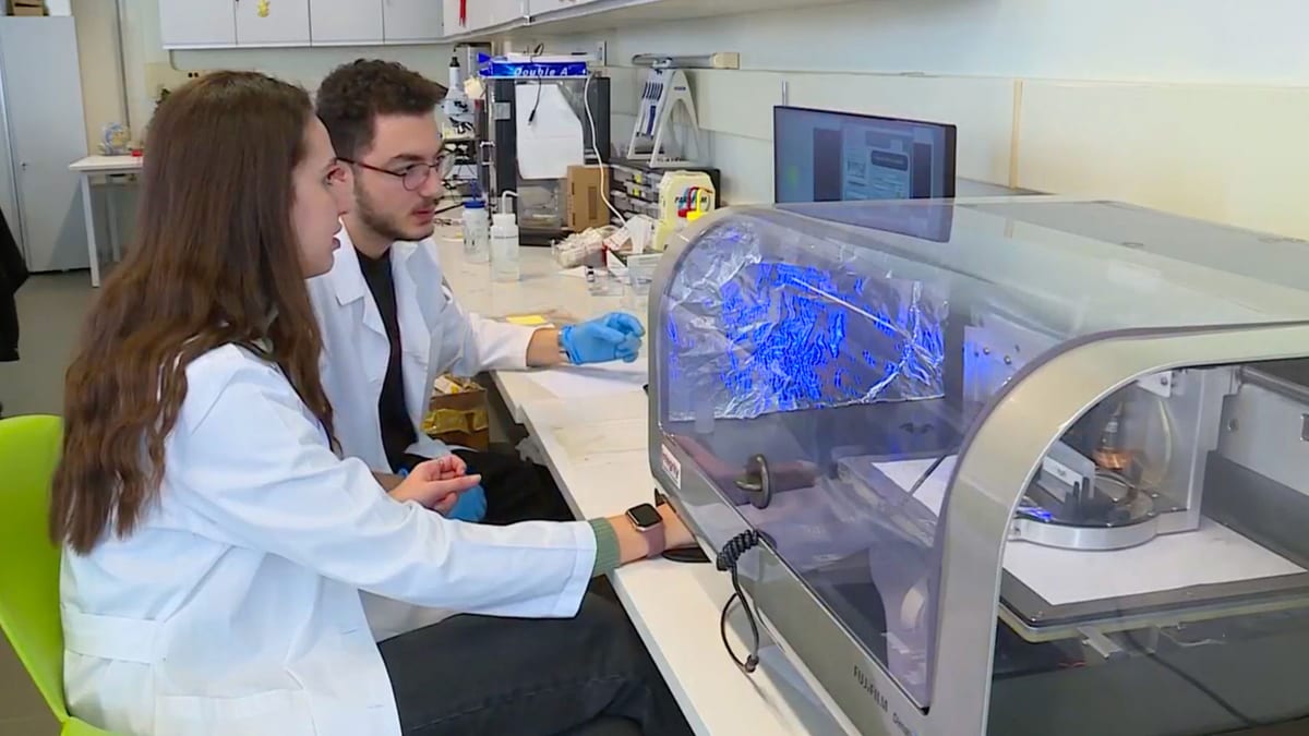 Two biomedical engineering students work with analytical laboratory equipment.
