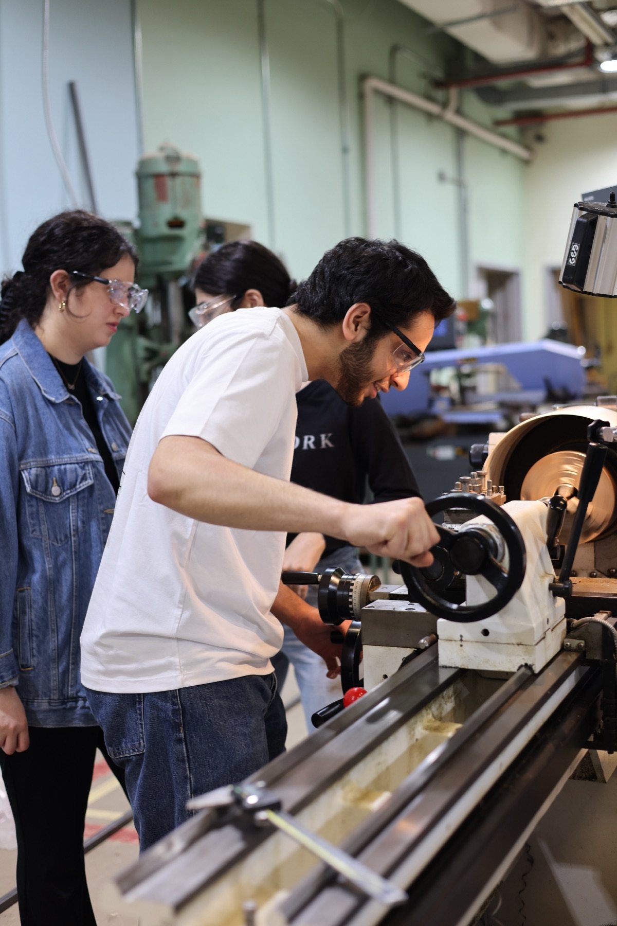 MSFEA students learn together while operating a machine tool in an engineering workshop.